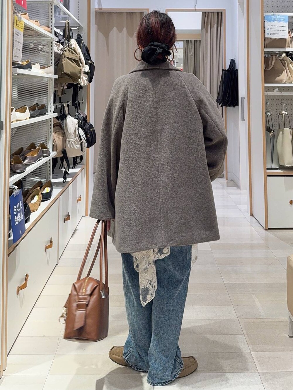 ブラウン系のボストンバッグ、ブルー系のデニムパンツ、ブラウン系のチェスターコートを着用したレディースの秋コーディネートの6枚目の写真