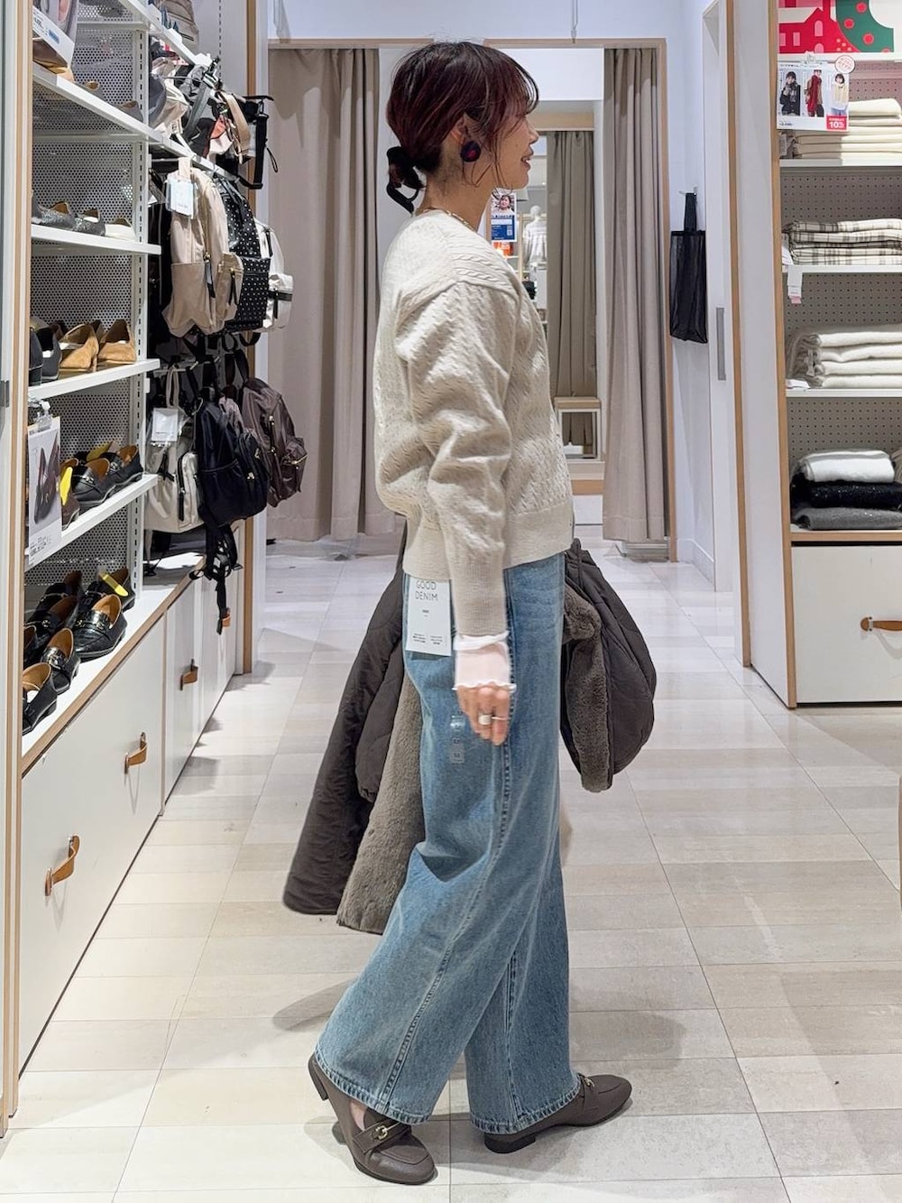 ホワイト系のショルダーバッグ、ブルー系のデニムパンツ、ブラウン系のブルゾンを着用したレディースの冬コーディネートの5枚目の写真