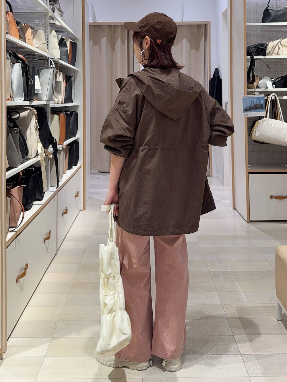 ベージュ系のトートバッグ、ブラウン系のパーカー、ピンク系のデニムパンツを着用したレディースの春コーディネートの5枚目の写真