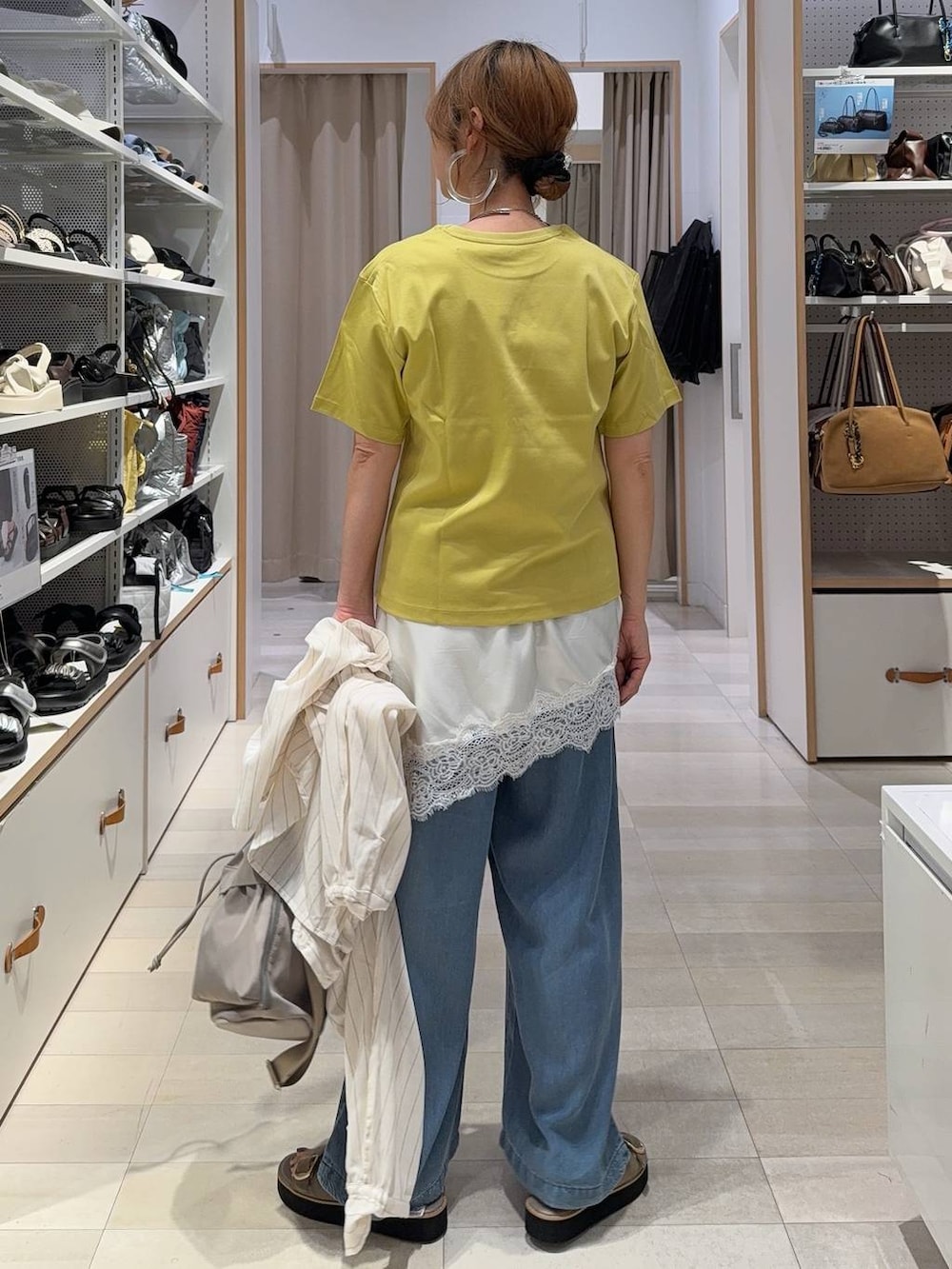 ブラウン系のトートバッグ、ブラック系のワンピース、ブルー系のデニムパンツを着用したレディースの夏コーディネートの7枚目の写真