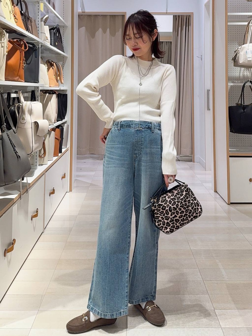 ホワイト系のスニーカー、ブルー系のデニムパンツ、ホワイト系のニット/セーターを着用したレディースの冬コーディネートの3枚目の写真