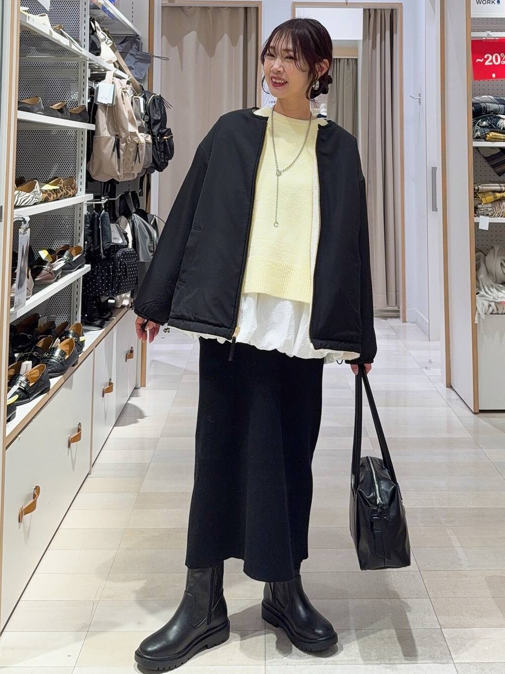 ブラック系のボストンバッグ、ホワイト系のブルゾン、イエロー系のニット/セーターを着用したレディースの冬コーディネートの2枚目の写真