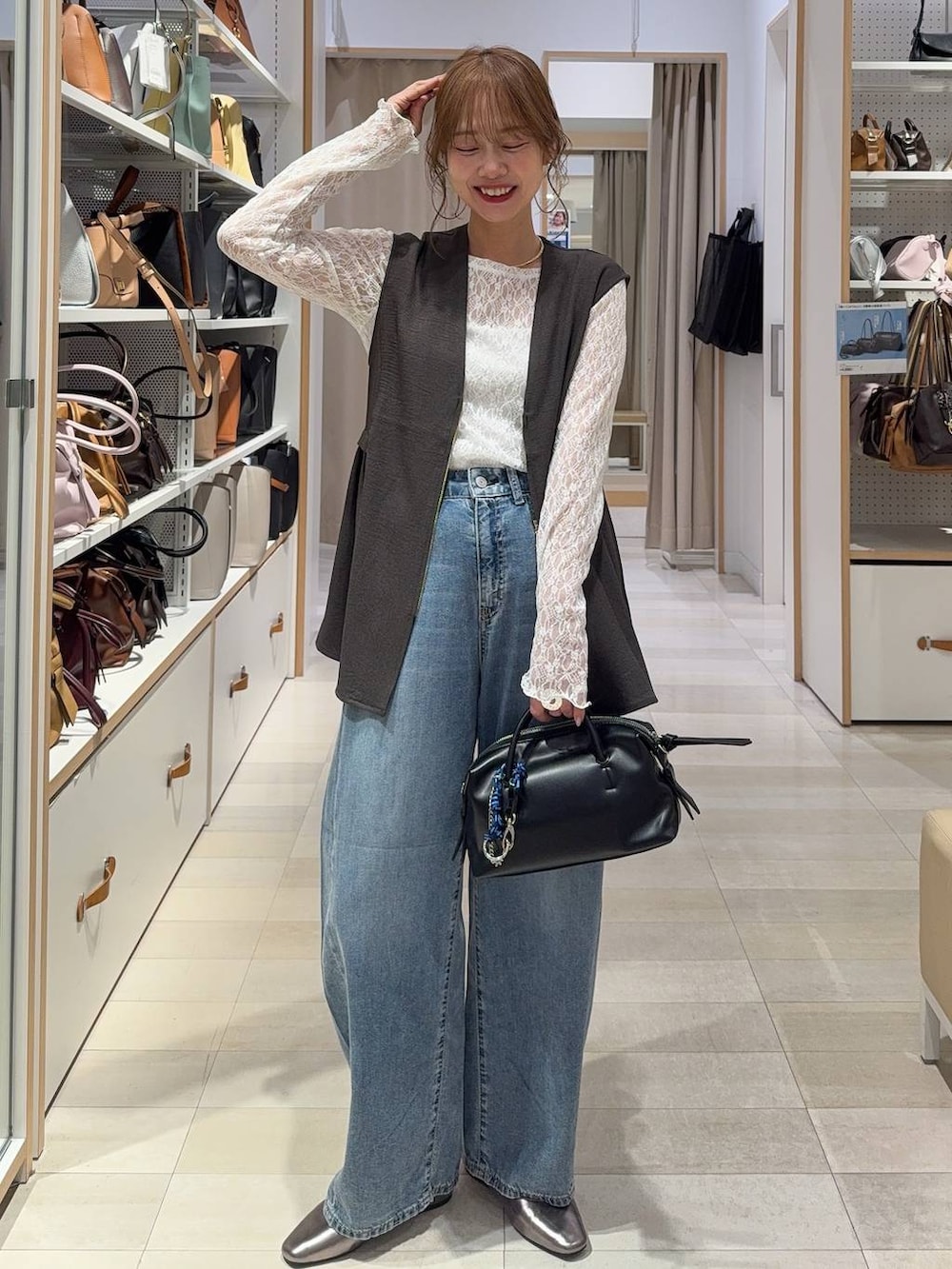 ブルー系のデニムパンツ、ブラウン系のテーラードジャケット、グレー系のベストを着用したレディースの春コーディネートの5枚目の写真