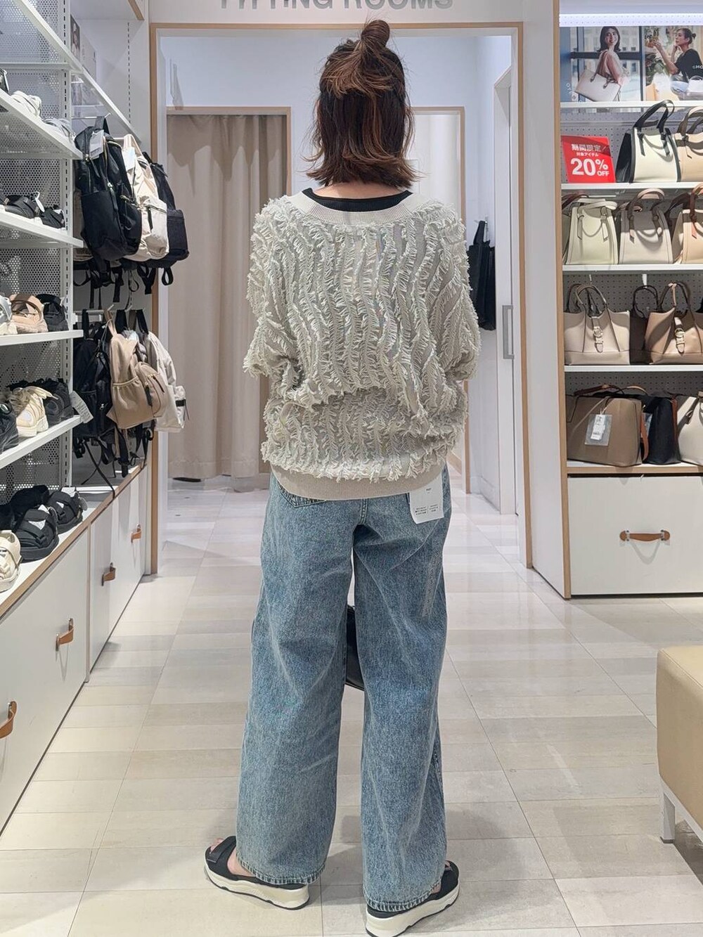 ブルー系のデニムパンツ、ブラック系のショルダーバッグ、ブラック系のタンクトップを着用したレディースの春コーディネートの4枚目の写真