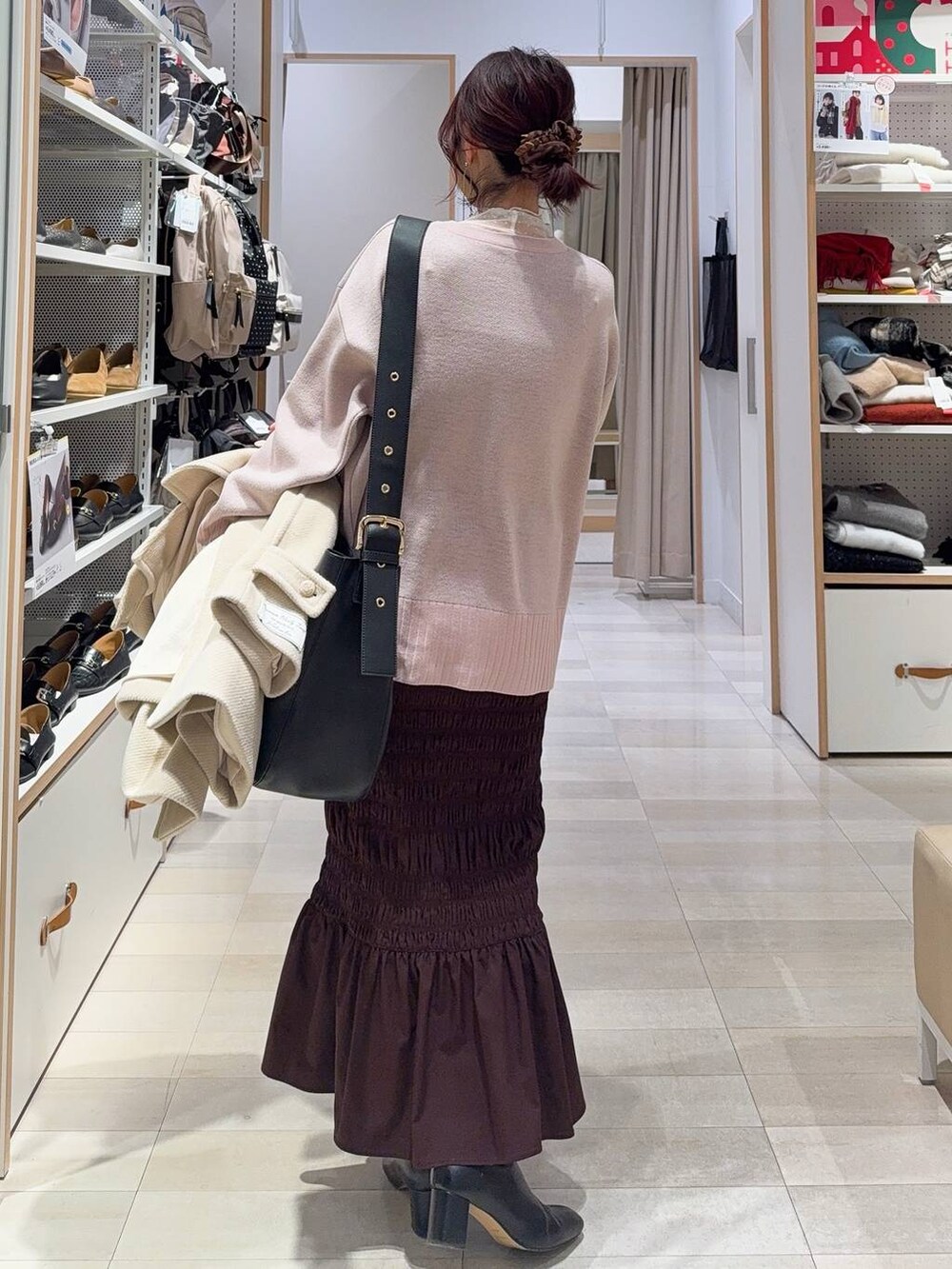 ブラック系のショルダーバッグ、ホワイト系のTシャツ/カットソー、ブラック系のブーツを着用したレディースの冬コーディネートの9枚目の写真