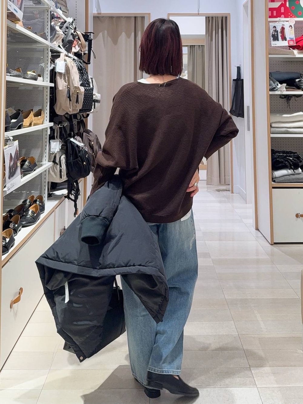 ブラック系のダウンジャケット/コート、ブラック系のボストンバッグ、ブルー系のデニムパンツを着用したレディースの冬コーディネートの8枚目の写真