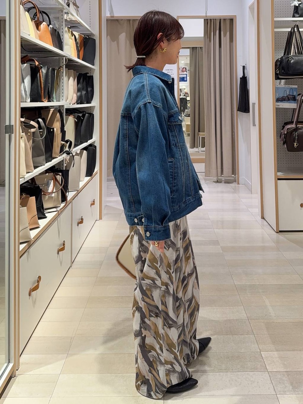 ブラック系のパンプス、ベージュ系のトートバッグ、ブルー系のデニムジャケットを着用したレディースの春コーディネートの3枚目の写真