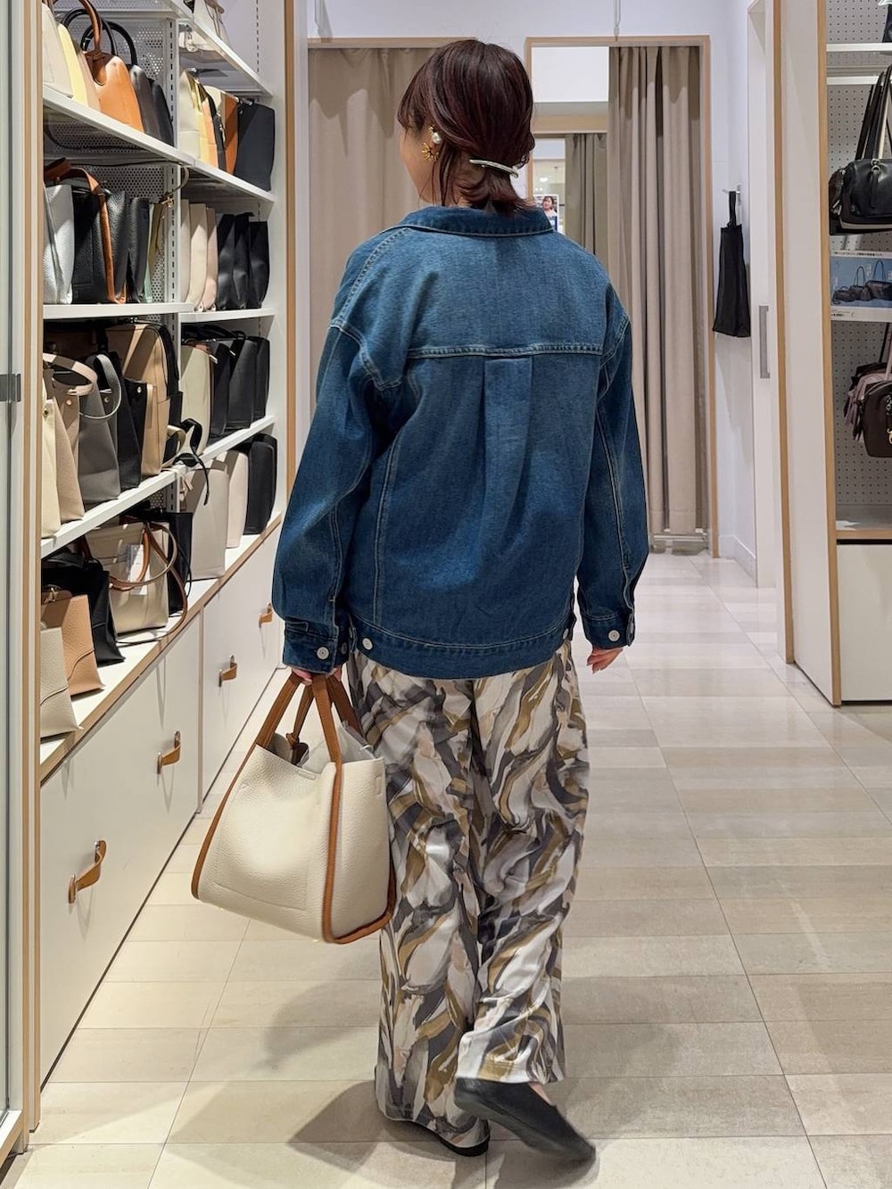 ブラック系のパンプス、ベージュ系のトートバッグ、ブルー系のデニムジャケットを着用したレディースの春コーディネートの4枚目の写真