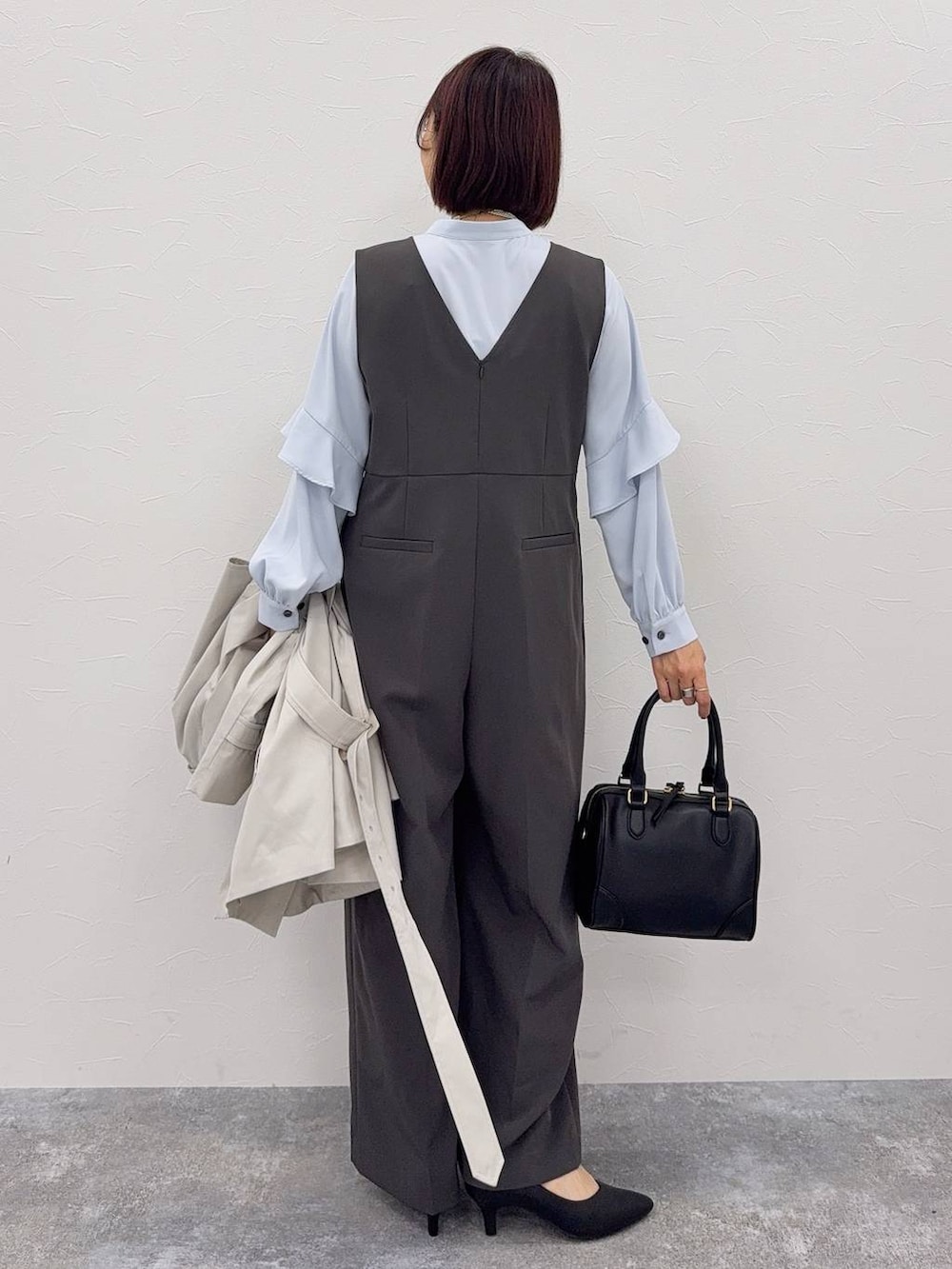 グレー系のセットアップ、ブラック系のボストンバッグ、その他のネックレスを着用したレディースの秋コーディネートの4枚目の写真