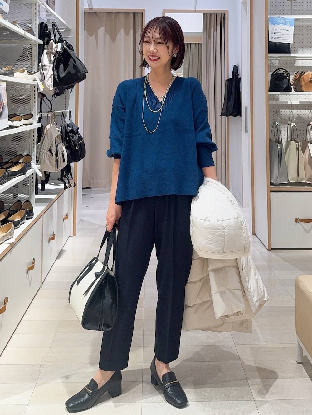 ブラック系のローファー、ホワイト系のショルダーバッグ、ベージュ系のダウンジャケット/コートを着用したレディースの秋コーディネートの3枚目の写真