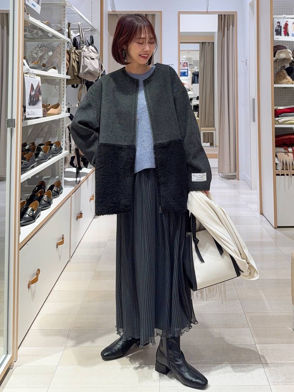 ホワイト系のショルダーバッグ、グレー系のノーカラージャケット、ブラック系のブーツを着用したレディースの秋コーディネートの2枚目の写真