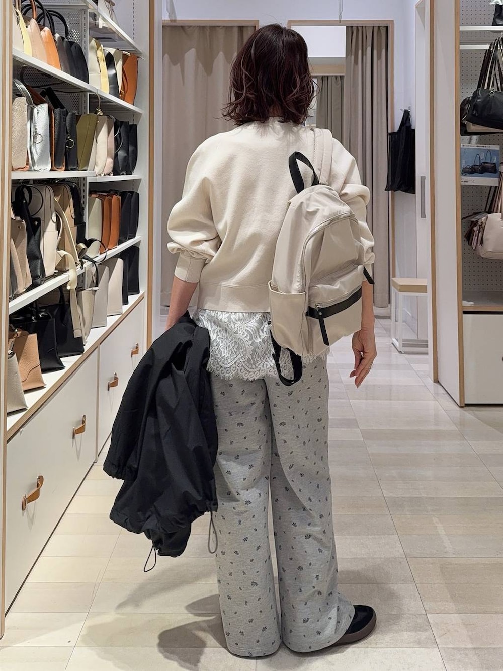 ブラック系のスニーカー、ホワイト系のバックパック/リュック、ブラック系のマウンテンパーカーを着用したレディースの春コーディネートの6枚目の写真