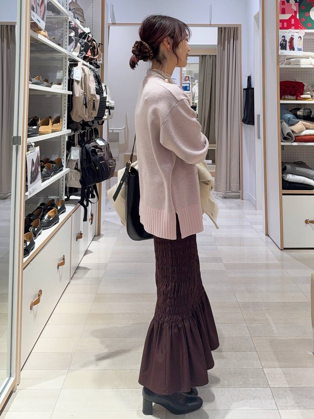 ブラック系のショルダーバッグ、ホワイト系のTシャツ/カットソー、ブラック系のブーツを着用したレディースの冬コーディネートの8枚目の写真