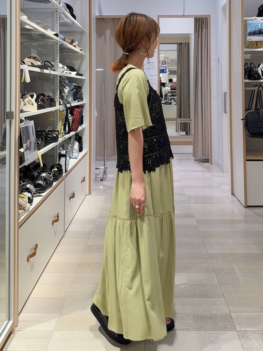グリーン系のワンピース、ブルー系のデニムパンツ、ブラック系のサンダルを着用したレディースの夏コーディネートの5枚目の写真