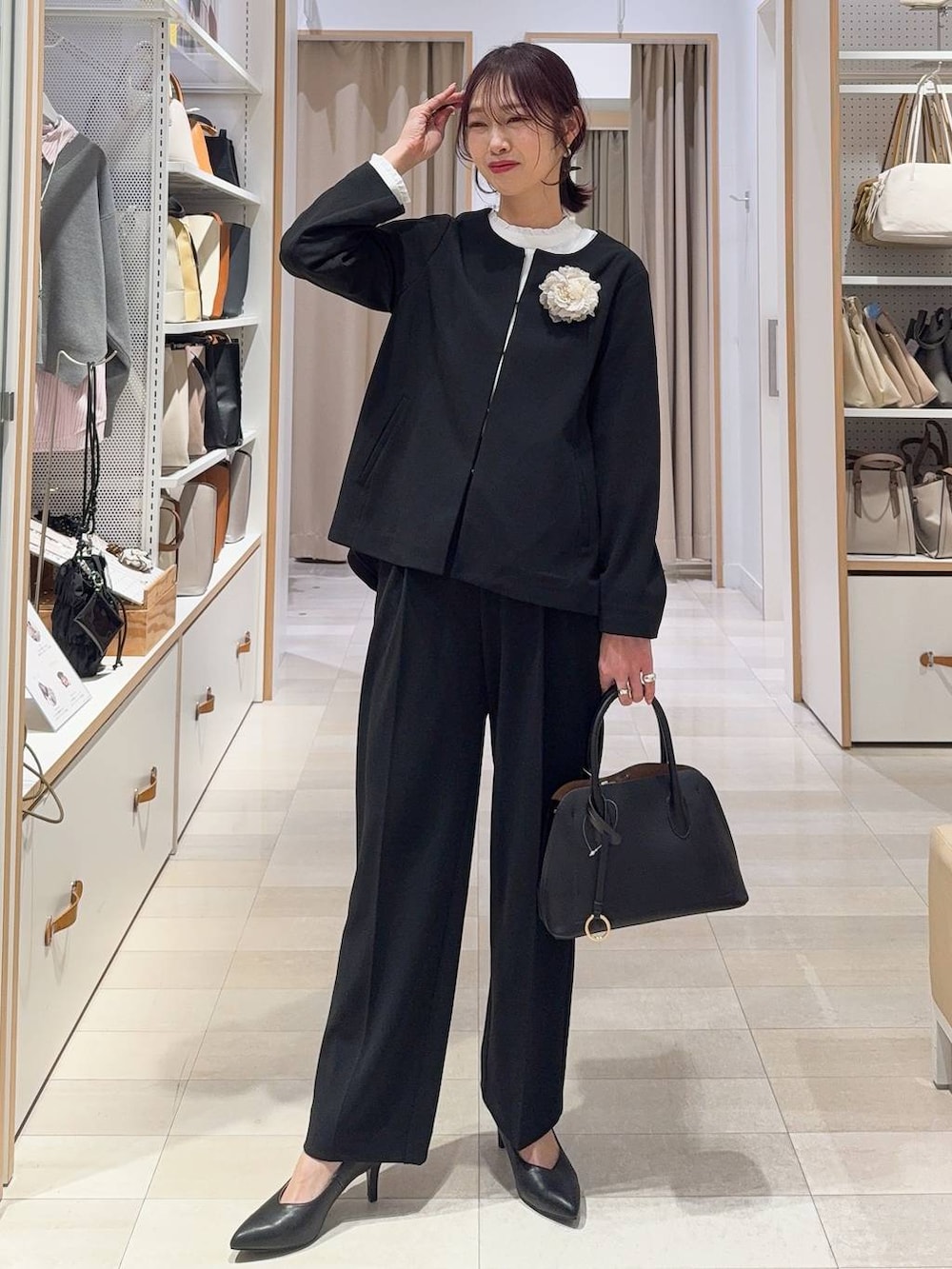 ブラック系のショルダーバッグ、ホワイト系のパンプス、ブラック系のセットアップを着用したレディースの冬コーディネートの2枚目の写真