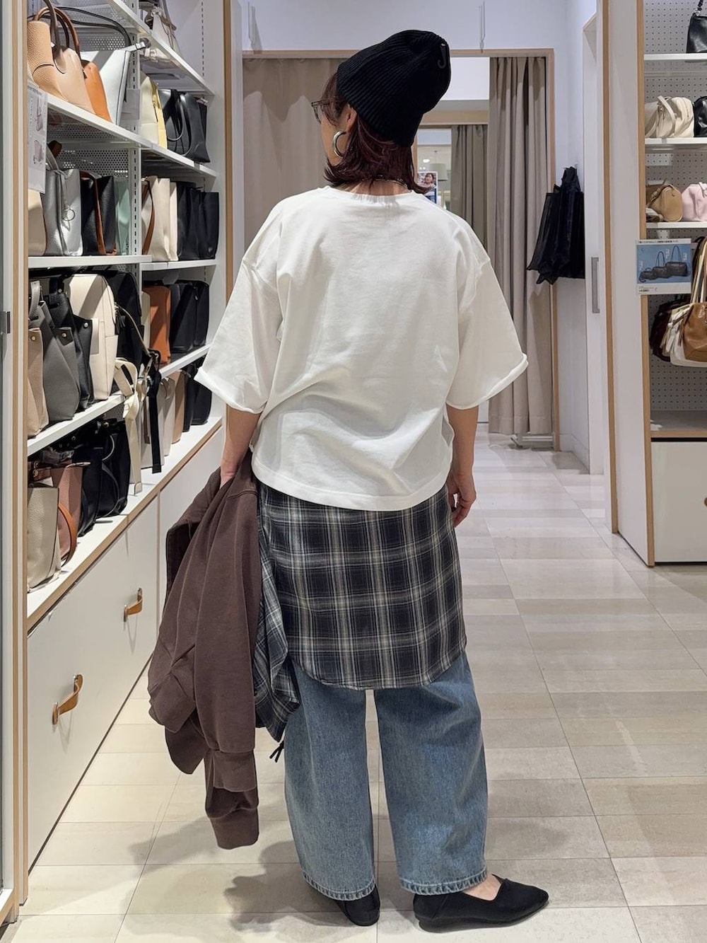 ブラック系のパンプス、ブラック系のハンドバッグ、ブルー系のデニムパンツを着用したレディースの春コーディネートの8枚目の写真