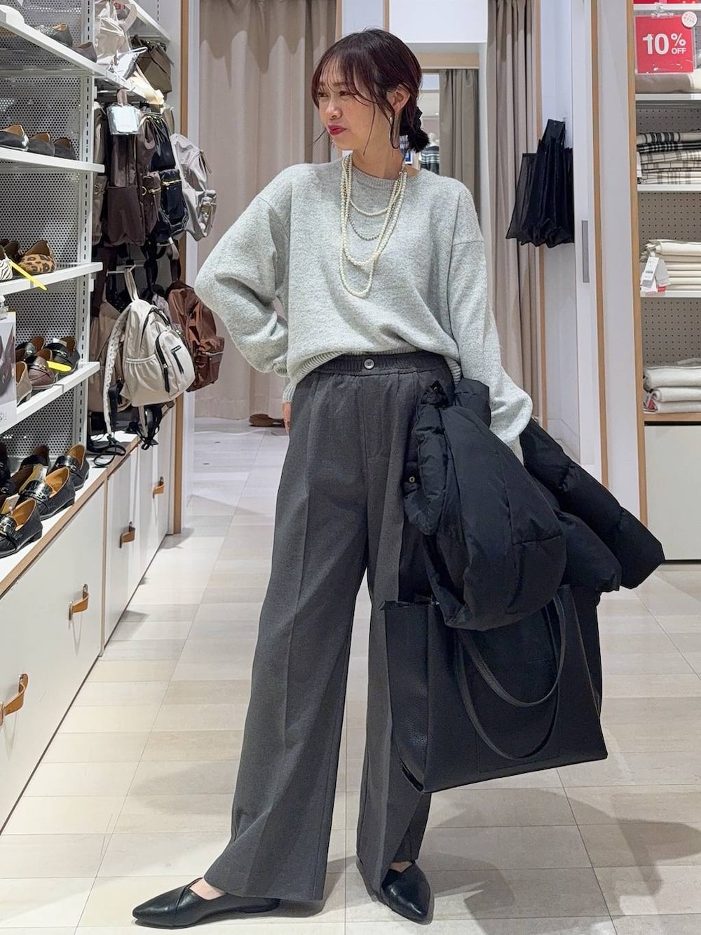 ブラック系のパンプス、ブラック系のダウンジャケット/コート、シルバー系のニット/セーターを着用したレディースの冬コーディネートの2枚目の写真