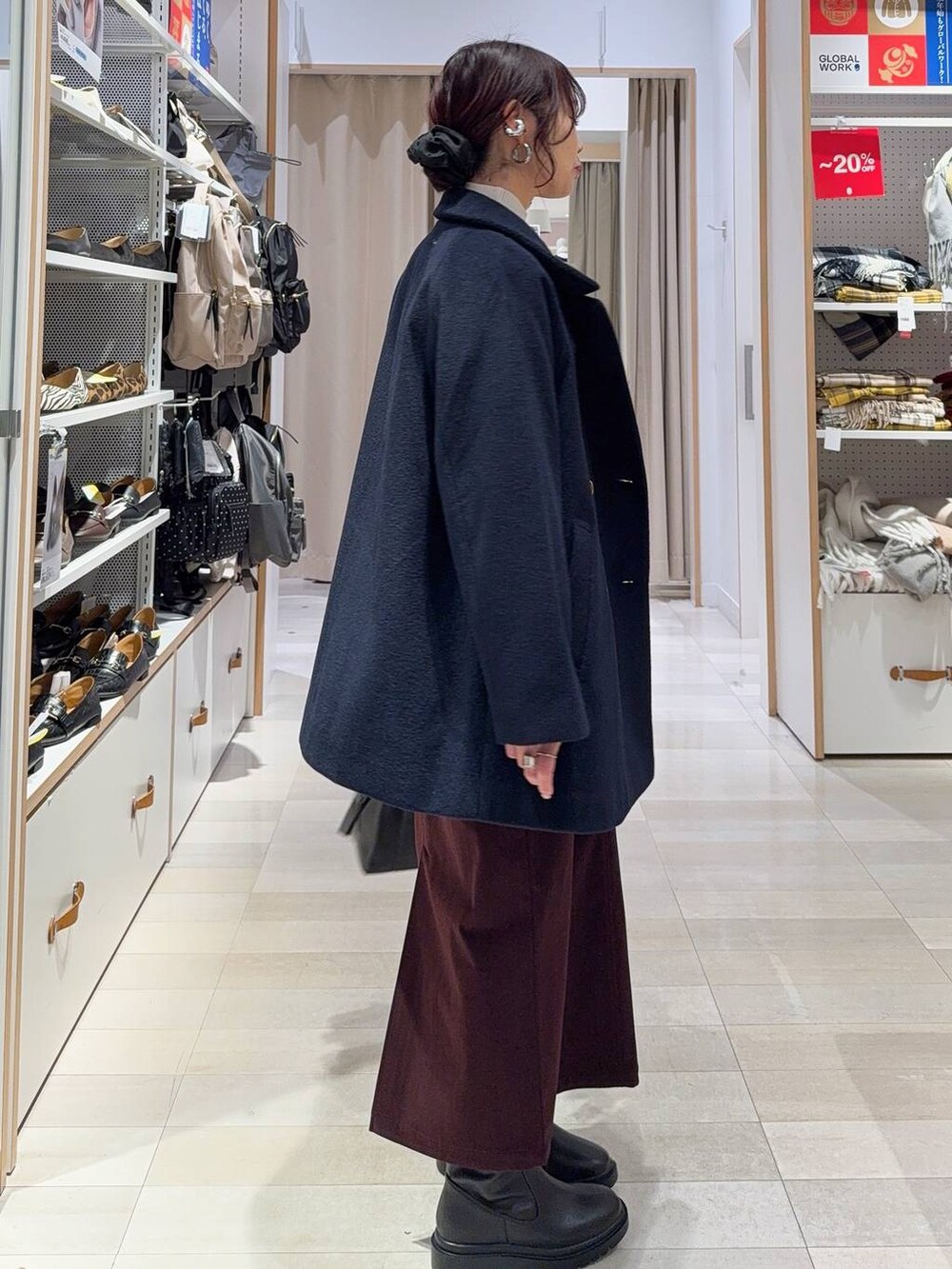 ブラック系のボストンバッグ、ブルー系のチェスターコート、レッド系のスカートを着用したレディースの冬コーディネートの4枚目の写真