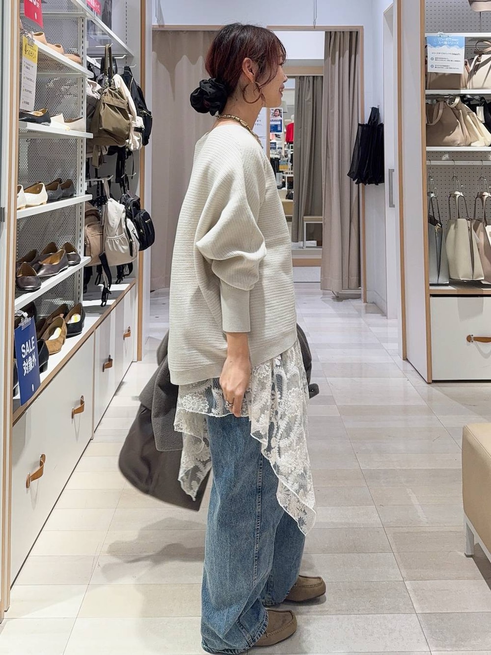 ブラウン系のボストンバッグ、ブルー系のデニムパンツ、ブラウン系のチェスターコートを着用したレディースの秋コーディネートの7枚目の写真