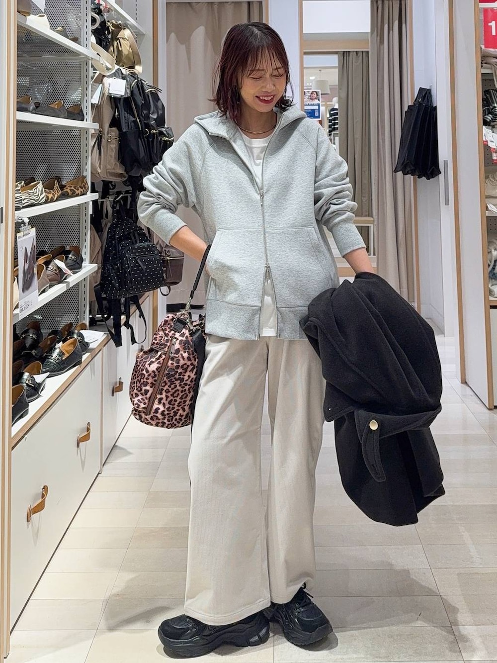 ブラック系のチェスターコート、グレー系のその他パンツ、ブラック系のスニーカーを着用したレディースの冬コーディネートの2枚目の写真