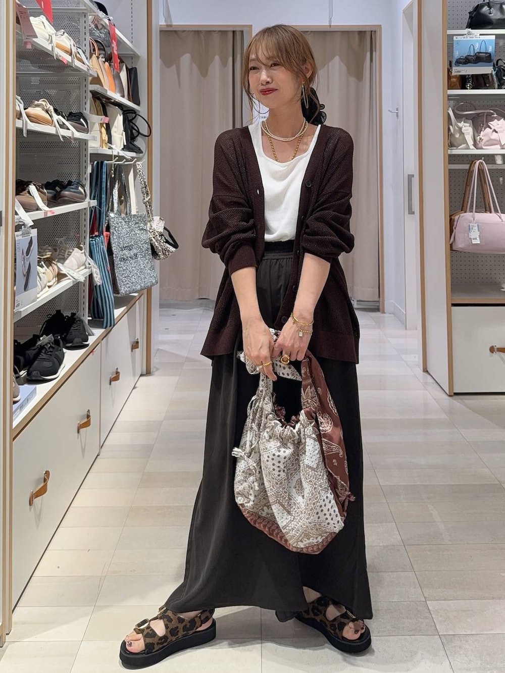 ホワイト系のパンプス、ベージュ系のボストンバッグ、ブラック系のその他パンツを着用したレディースの夏コーディネートの2枚目の写真