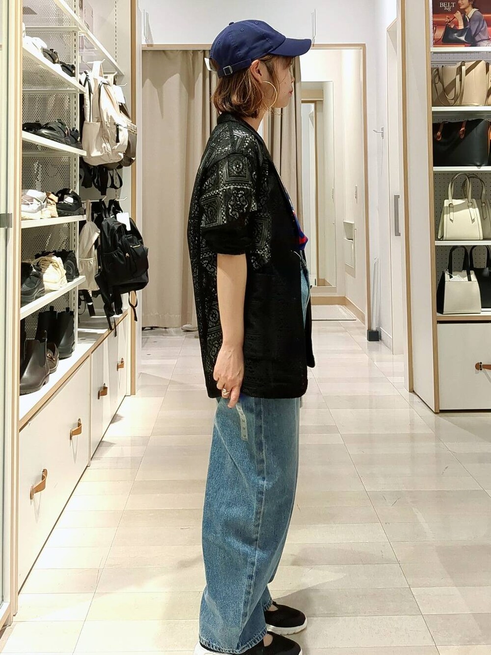 ブラック系のスニーカー、シルバー系のショルダーバッグ、ブルー系のデニムパンツを着用したレディースの春コーディネートの4枚目の写真