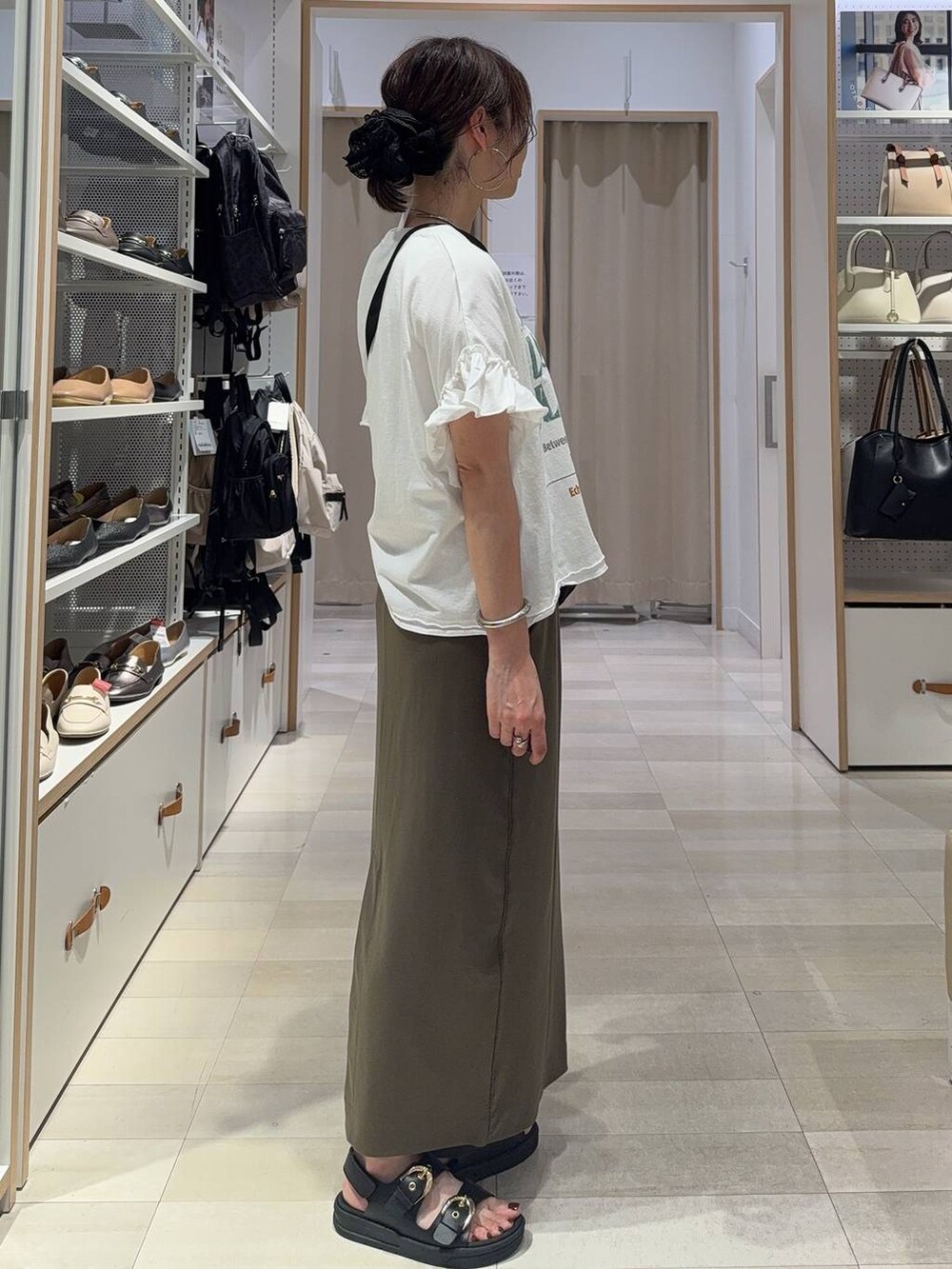 ブラック系のショルダーバッグ、ホワイト系のTシャツ/カットソー、グリーン系のスカートを着用したレディースの夏コーディネートの4枚目の写真