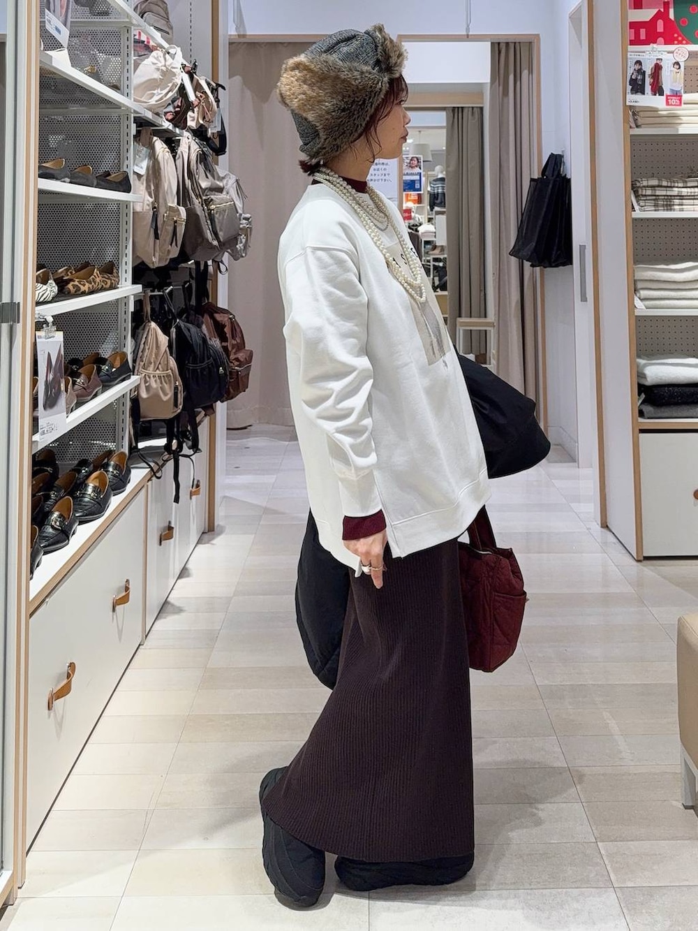 レッド系のトートバッグ、ブラック系のダウンジャケット/コート、レッド系のニット/セーターを着用したレディースの冬コーディネートの8枚目の写真