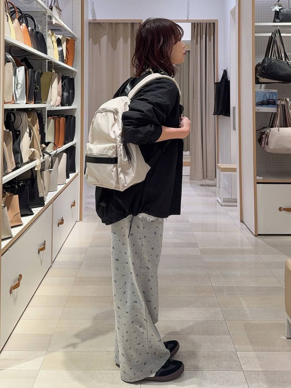 ブラック系のスニーカー、ホワイト系のバックパック/リュック、ブラック系のマウンテンパーカーを着用したレディースの春コーディネートの3枚目の写真