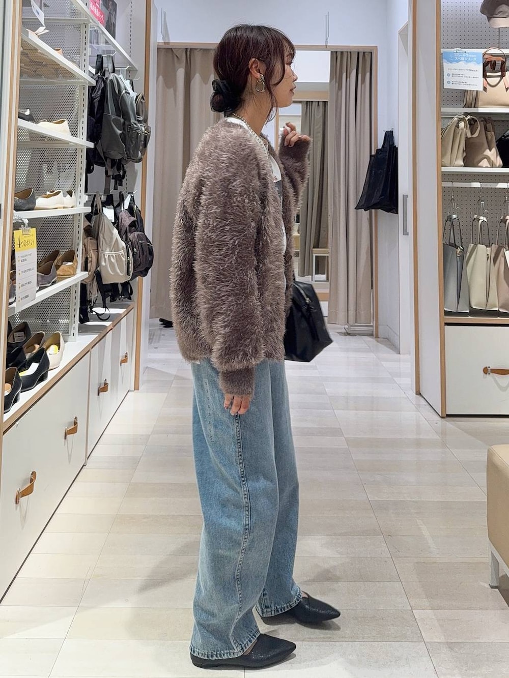 ブラック系のパンプス、ブラック系のボストンバッグ、ブルー系のデニムパンツを着用したレディースの秋コーディネートの4枚目の写真