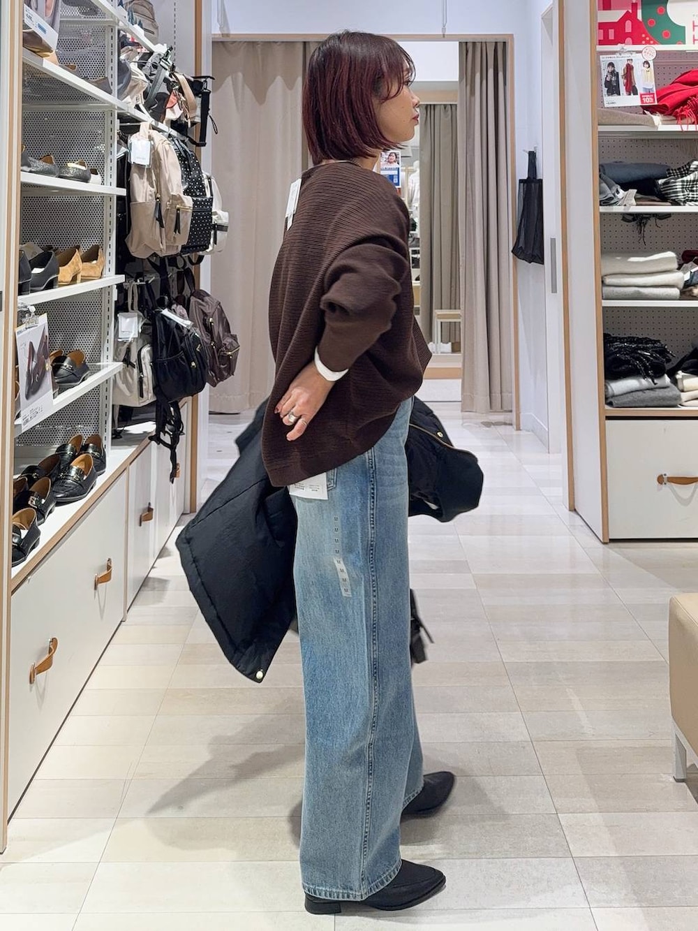 ブラック系のダウンジャケット/コート、ブラック系のボストンバッグ、ブルー系のデニムパンツを着用したレディースの冬コーディネートの7枚目の写真