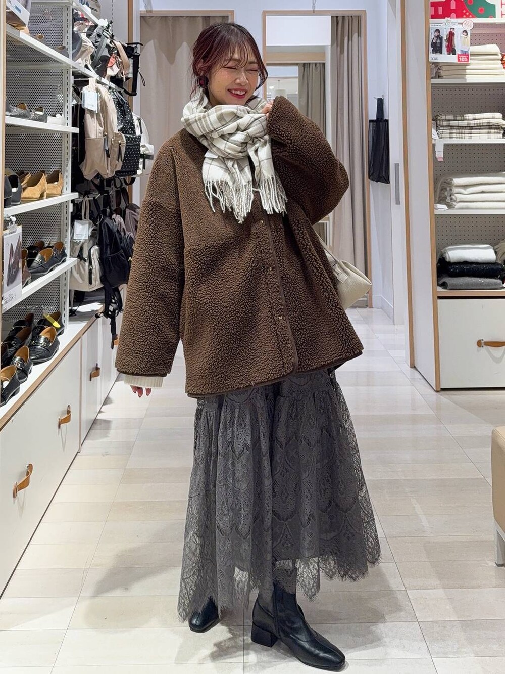 ベージュ系のショルダーバッグ、ブラック系のブーツ、ブラウン系のテーラードジャケットを着用したレディースの冬コーディネートの3枚目の写真