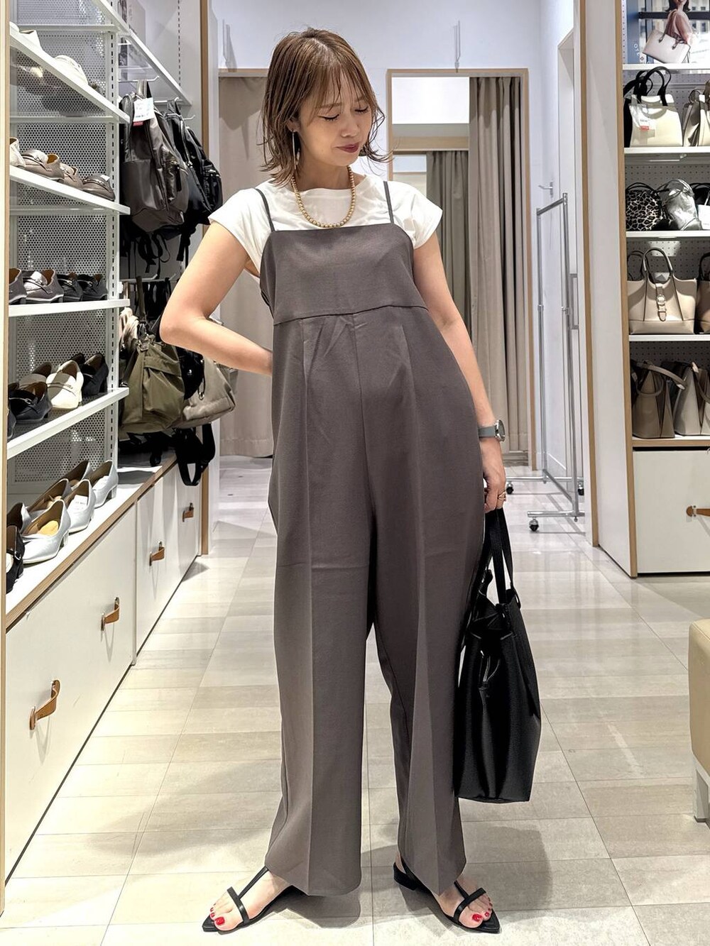 ブルー系のデニムパンツ、ブラック系のトートバッグ、グリーン系のTシャツ/カットソーを着用したレディースの春コーディネートの3枚目の写真