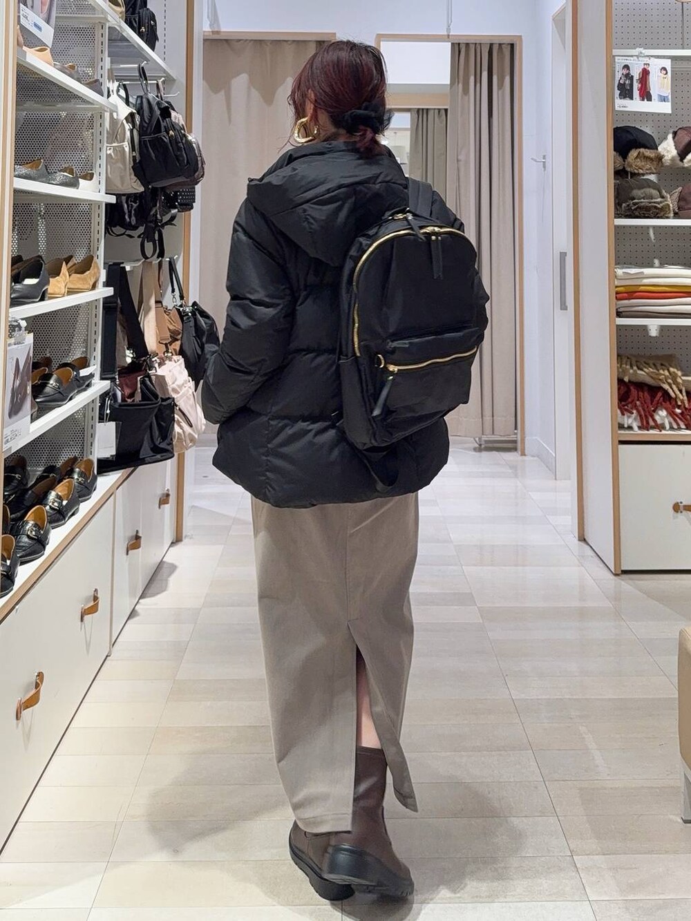 ブラック系のダウンジャケット/コート、ブラウン系のスカート、ホワイト系のニット/セーターを着用したレディースの冬コーディネートの4枚目の写真