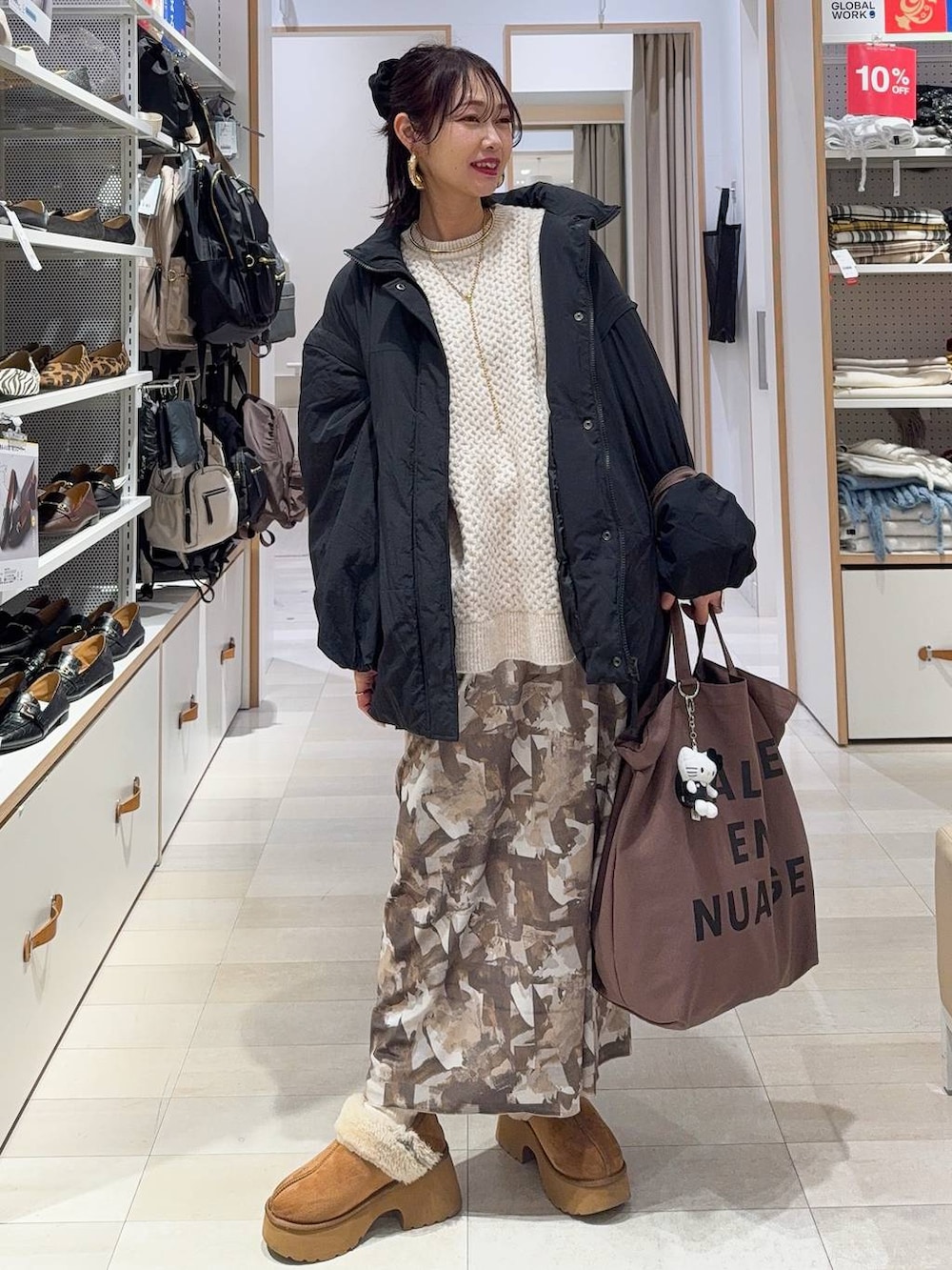 ブラック系のその他アウター、イエロー系のブーツ、ホワイト系のニット/セーターを着用したレディースの冬コーディネートの3枚目の写真