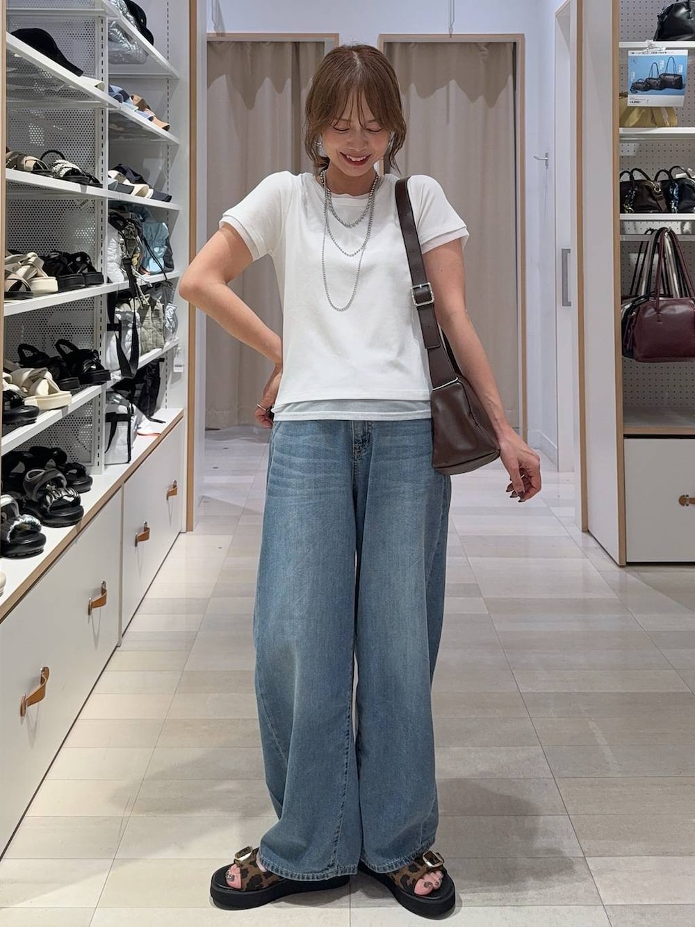 レッド系のボストンバッグ、ブルー系のデニムパンツ、ブラウン系のベストを着用したレディースの夏コーディネートの3枚目の写真