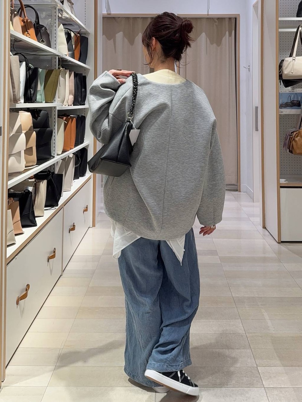 グレー系のブルゾン、イエロー系のカーディガン/ボレロ、ブラック系のスニーカーを着用したレディースの春コーディネートの5枚目の写真