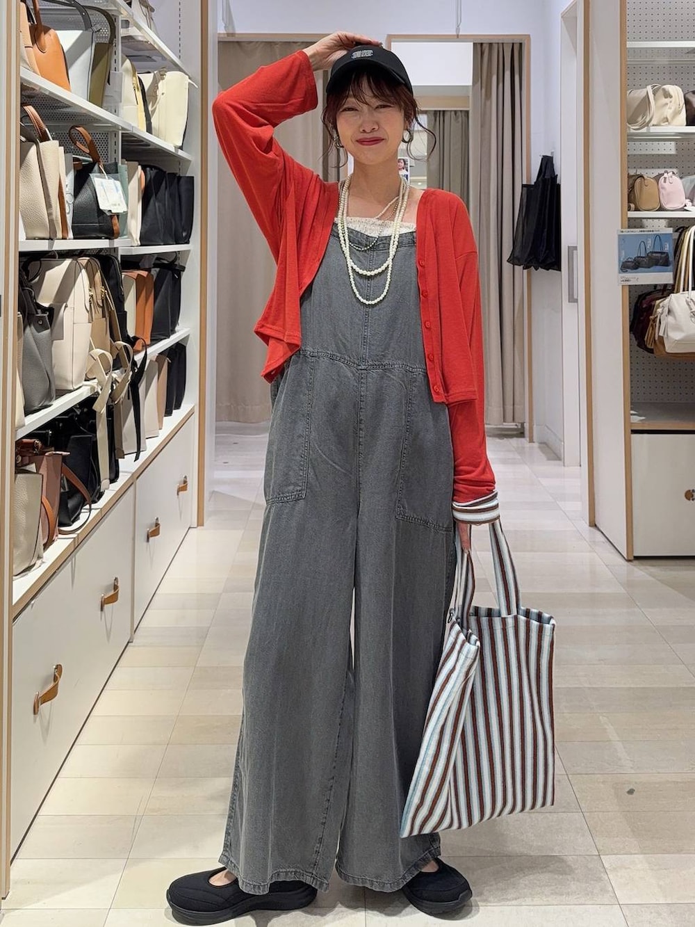 ブルー系のトートバッグ、オレンジ系のカーディガン/ボレロ、ブラック系のスニーカーを着用したレディースの春コーディネートの2枚目の写真