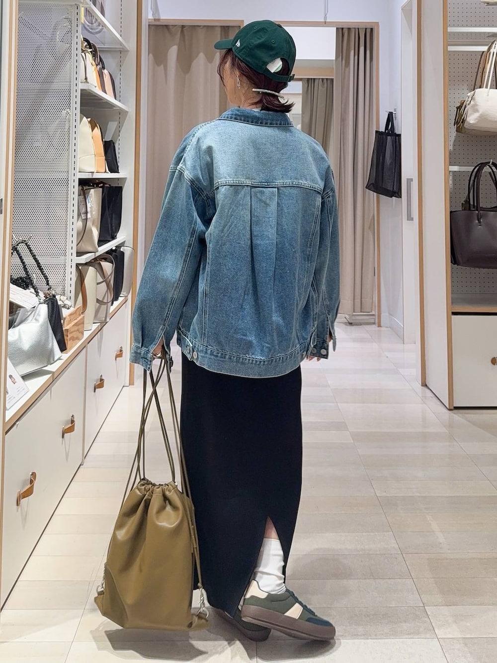 グリーン系のスニーカー、ブルー系のデニムジャケット、ブラック系のスカートを着用したレディースの冬コーディネートの6枚目の写真