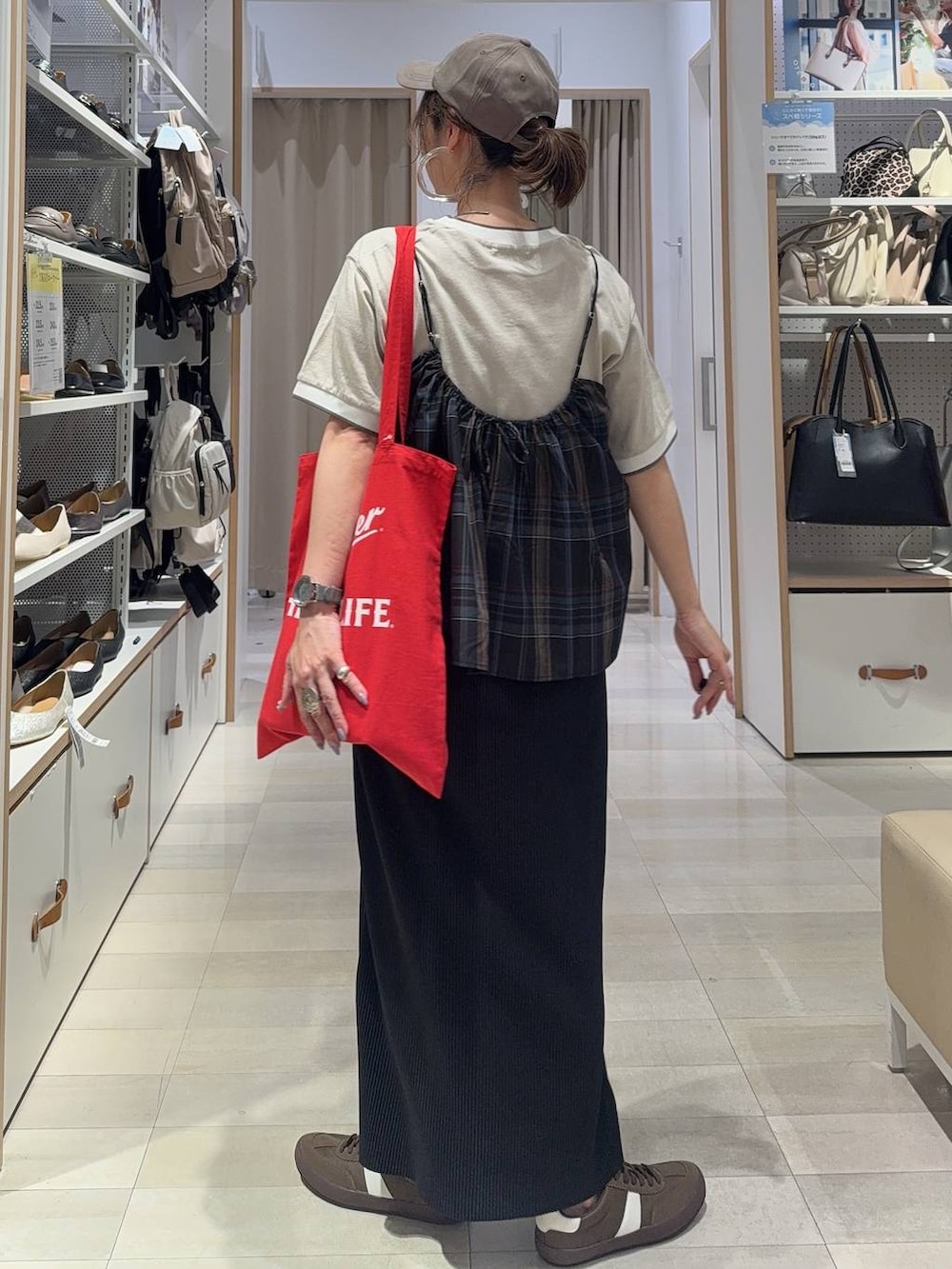 レッド系のトートバッグ、ブラック系のキャミソール、ブラック系のスカートを着用したレディースの夏コーディネートの3枚目の写真