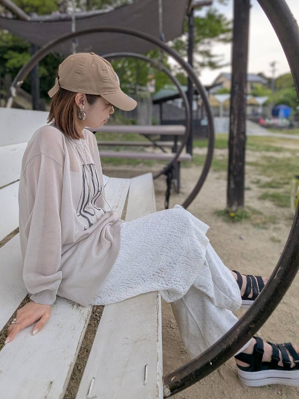 イエロー系のショルダーバッグ、ホワイト系のキャミソール、ベージュ系のニット/セーターを着用したレディースの春コーディネートの2枚目の写真