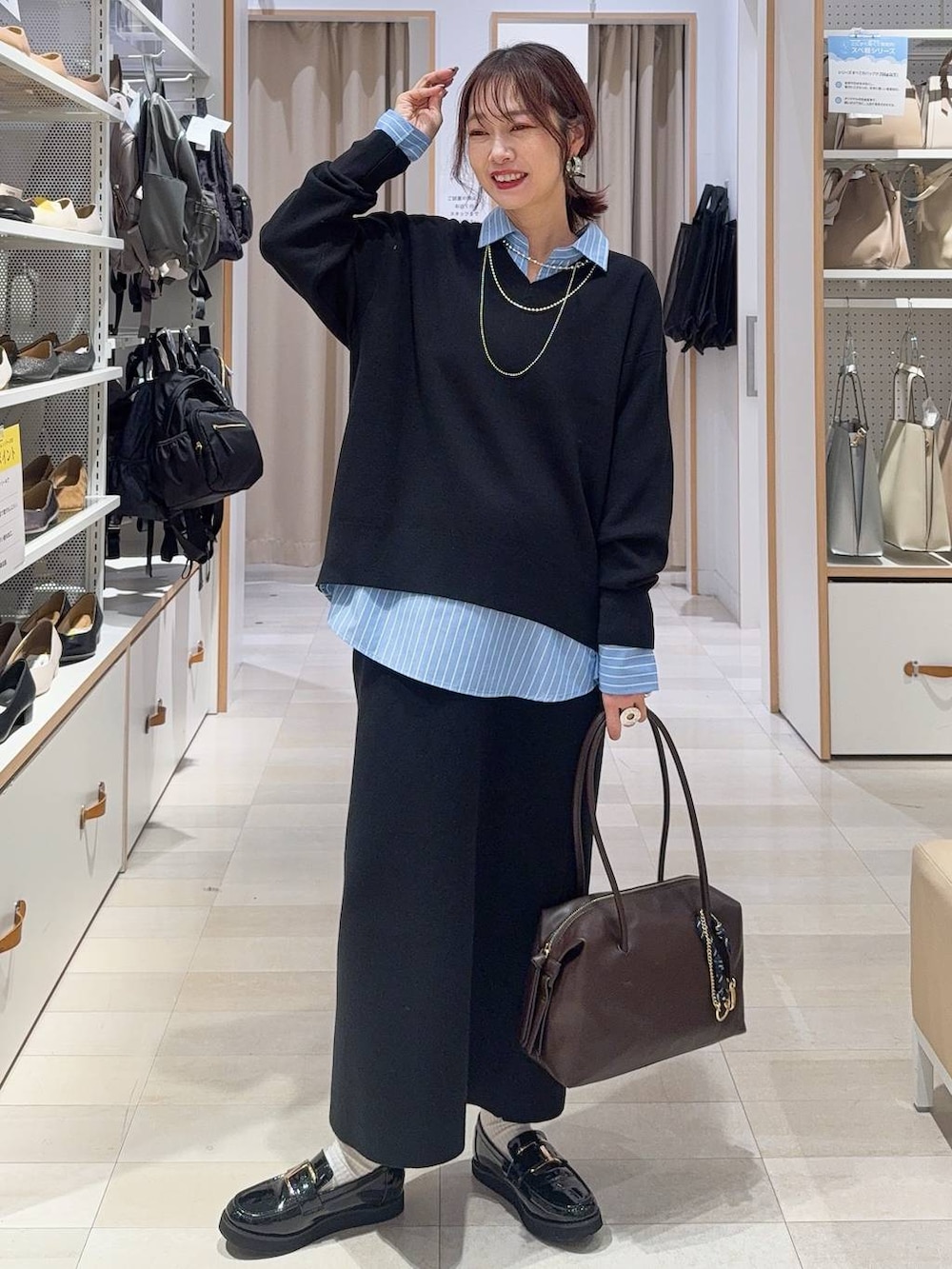 グリーン系のショルダーバッグ、ブラック系のチェスターコート、ブラック系のスウェットを着用したレディースの秋コーディネートの3枚目の写真