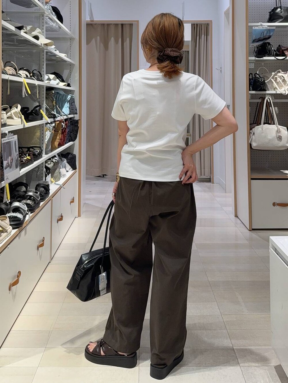 ブラック系のボストンバッグ、ブラウン系のその他パンツ、ホワイト系のTシャツ/カットソーを着用したレディースの夏コーディネートの7枚目の写真