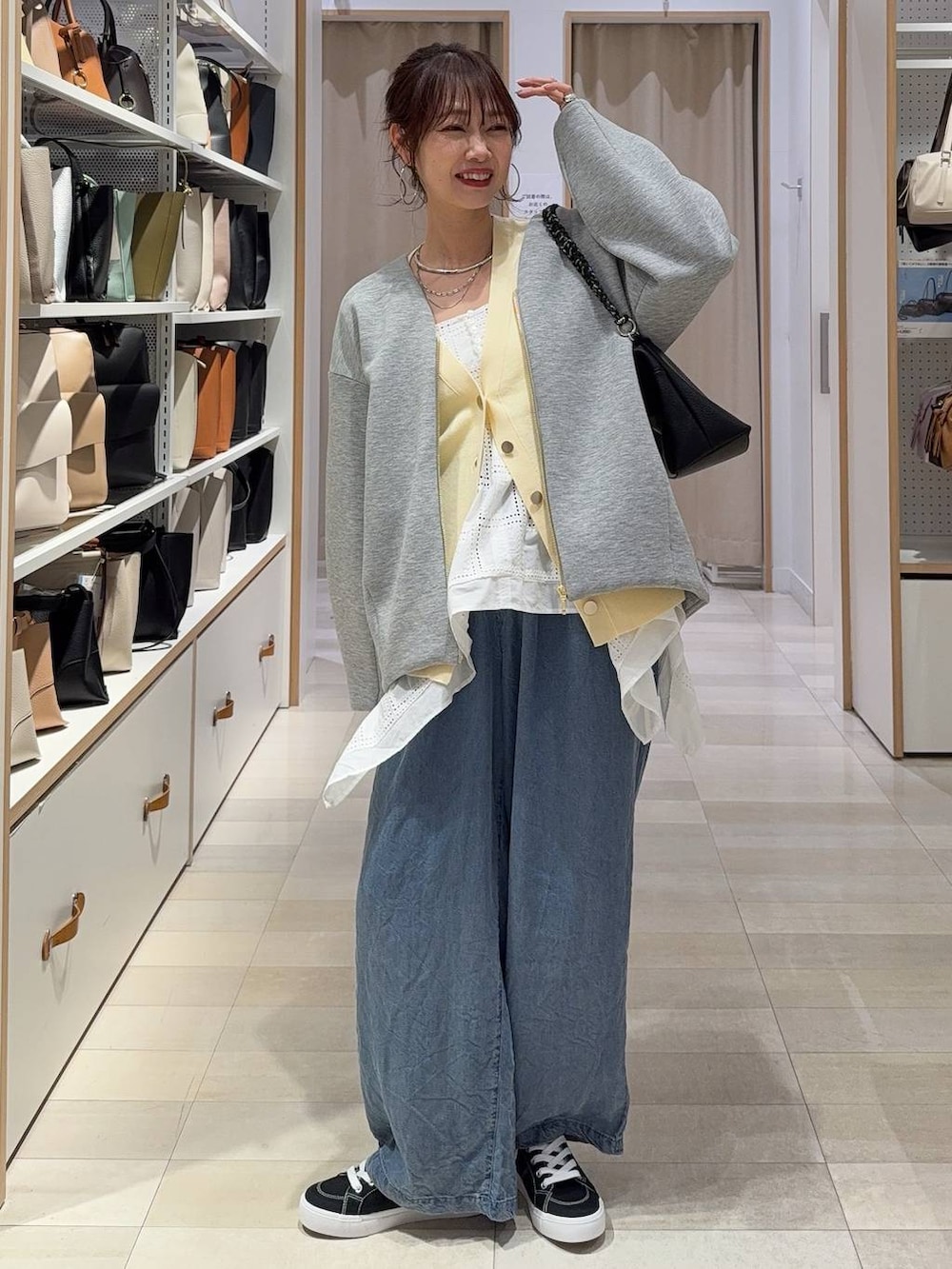 グレー系のブルゾン、イエロー系のカーディガン/ボレロ、ブラック系のスニーカーを着用したレディースの春コーディネートの2枚目の写真