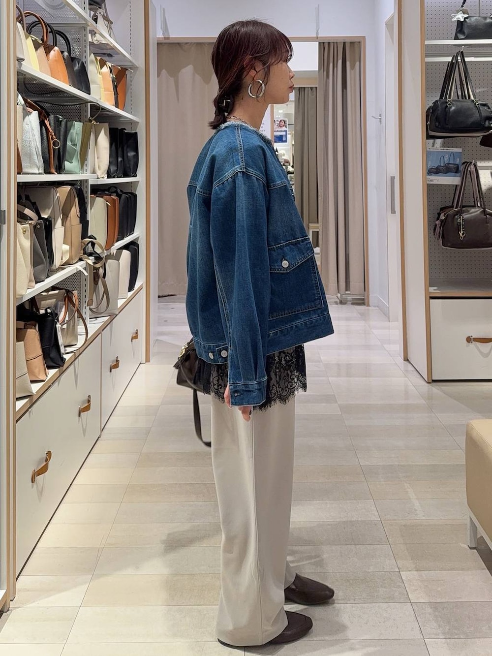 ブルー系のデニムジャケット、ブラウン系のボストンバッグ、ベージュ系のその他パンツを着用したレディースの春コーディネートの3枚目の写真