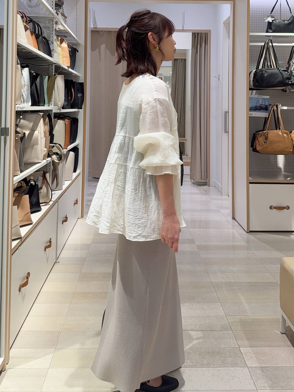 ホワイト系のスカート、ブラック系のパンプス、ゴールド系のネックレスを着用したレディースの春コーディネートの8枚目の写真