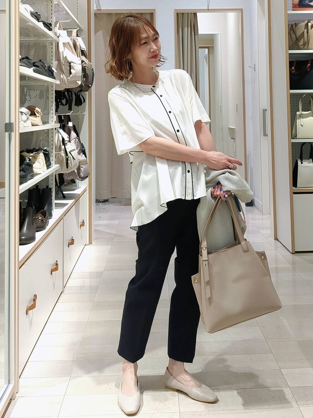 ベージュ系のパンプス、ブルー系のデニムパンツ、ブラック系のトートバッグを着用したレディースの春コーディネートの2枚目の写真