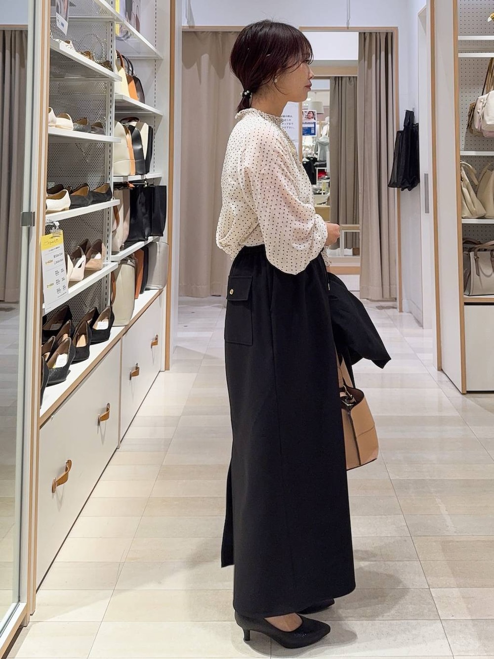 ブラック系のパンプス、ブラック系のノーカラージャケット、ベージュ系のショルダーバッグを着用したレディースの冬コーディネートの6枚目の写真