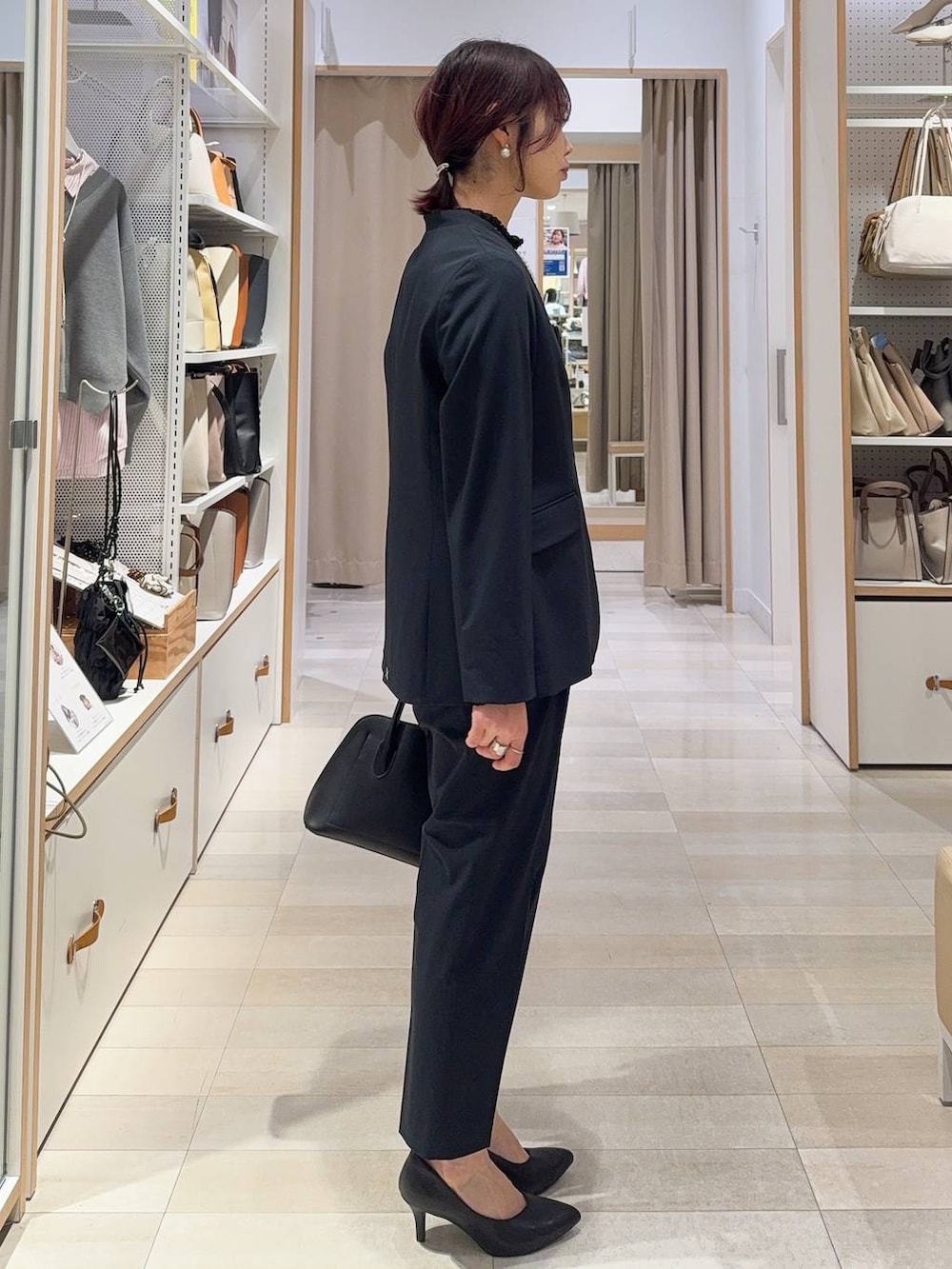 ブラック系のショルダーバッグ、ブルー系のスラックス、ブルー系のノーカラージャケットを着用したレディースの冬コーディネートの4枚目の写真