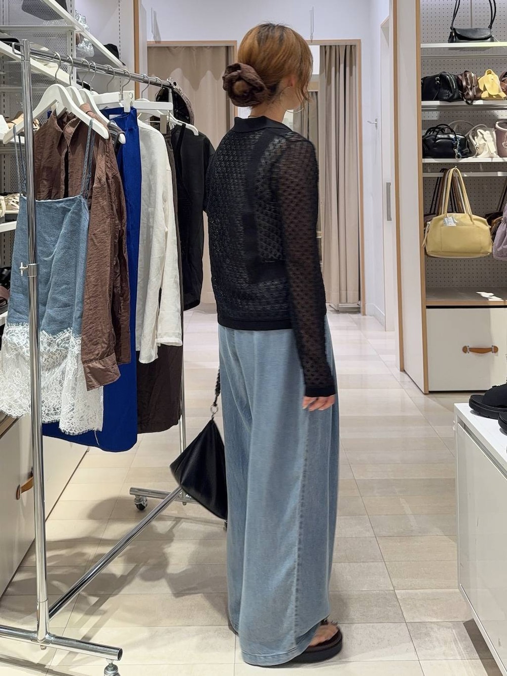 ブルー系のデニムパンツ、ブラック系のTシャツ/カットソー、ブラウン系のサンダルを着用したレディースの春コーディネートの6枚目の写真